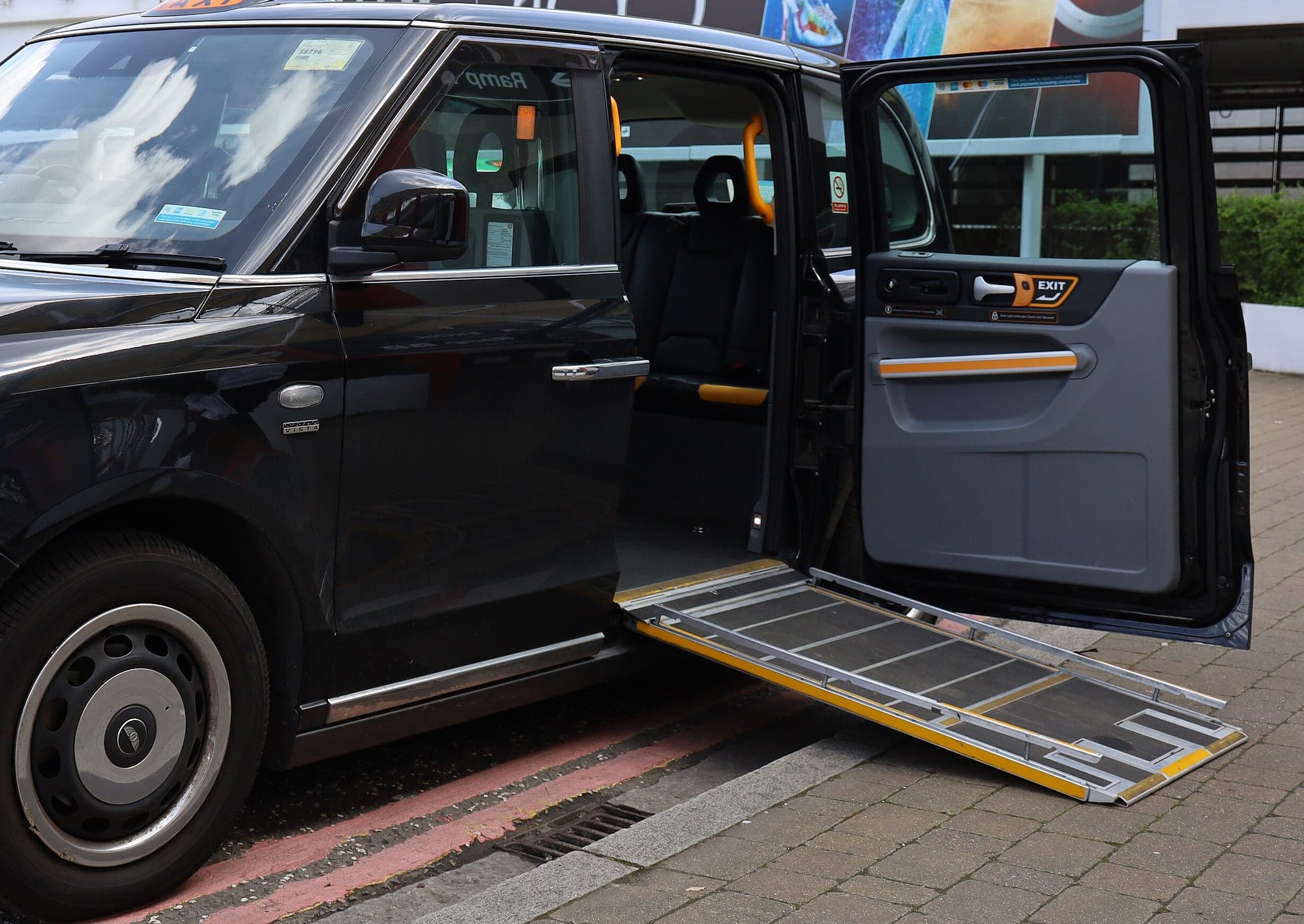 A wheelchair ramp deployed from the rear door of an accessible taxi.